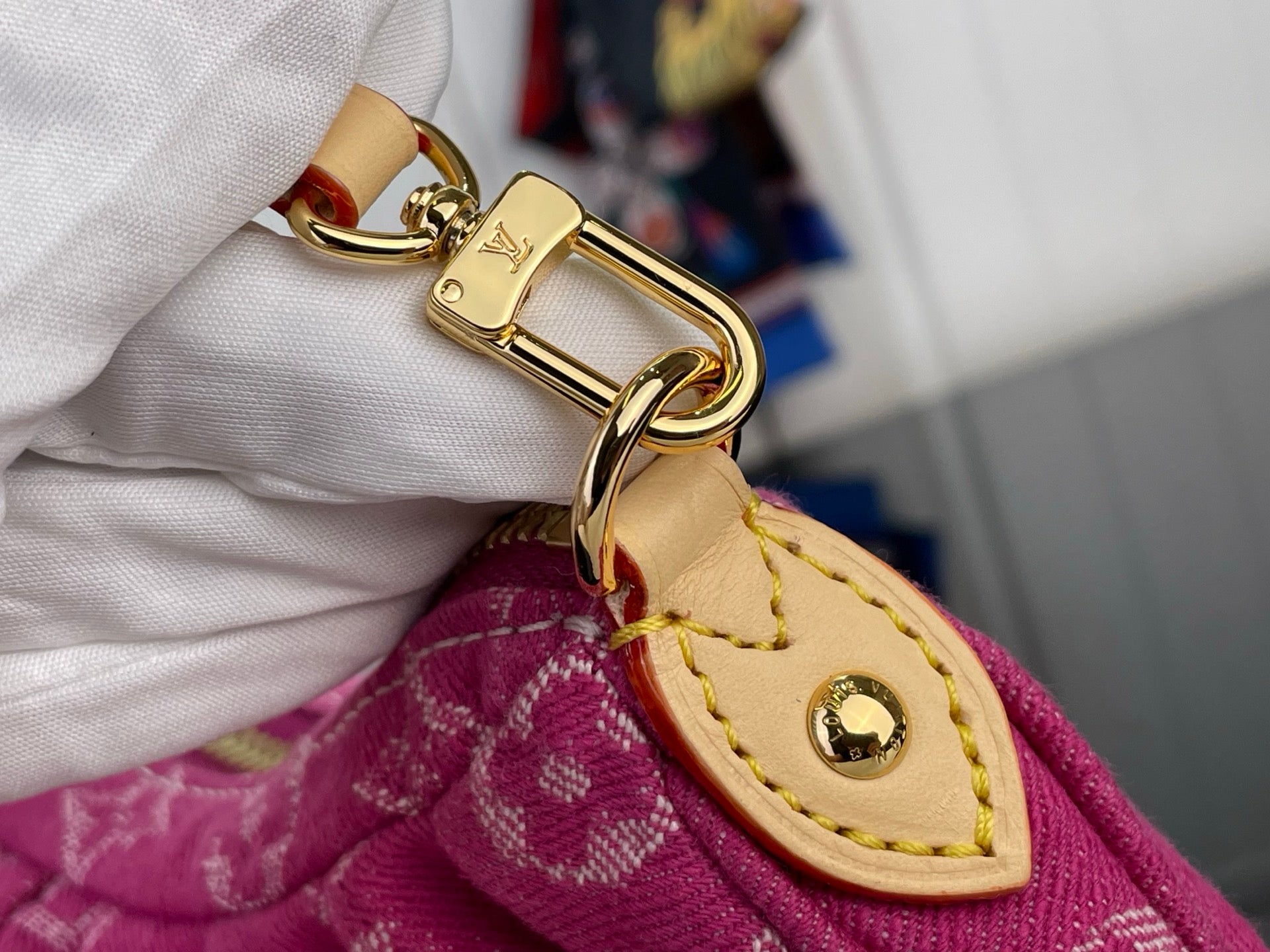 Louis Vuitton leather strap end with gold buckle and stitching on pink monogram bag.