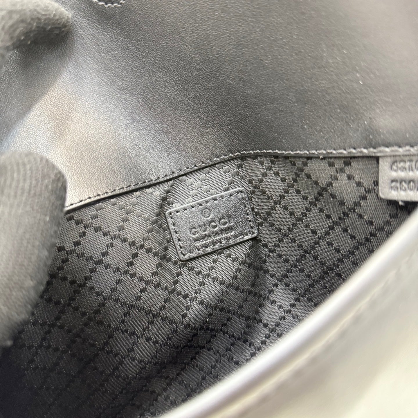 Gucci bag interior close-up with dark checkered lining and Gucci patch label