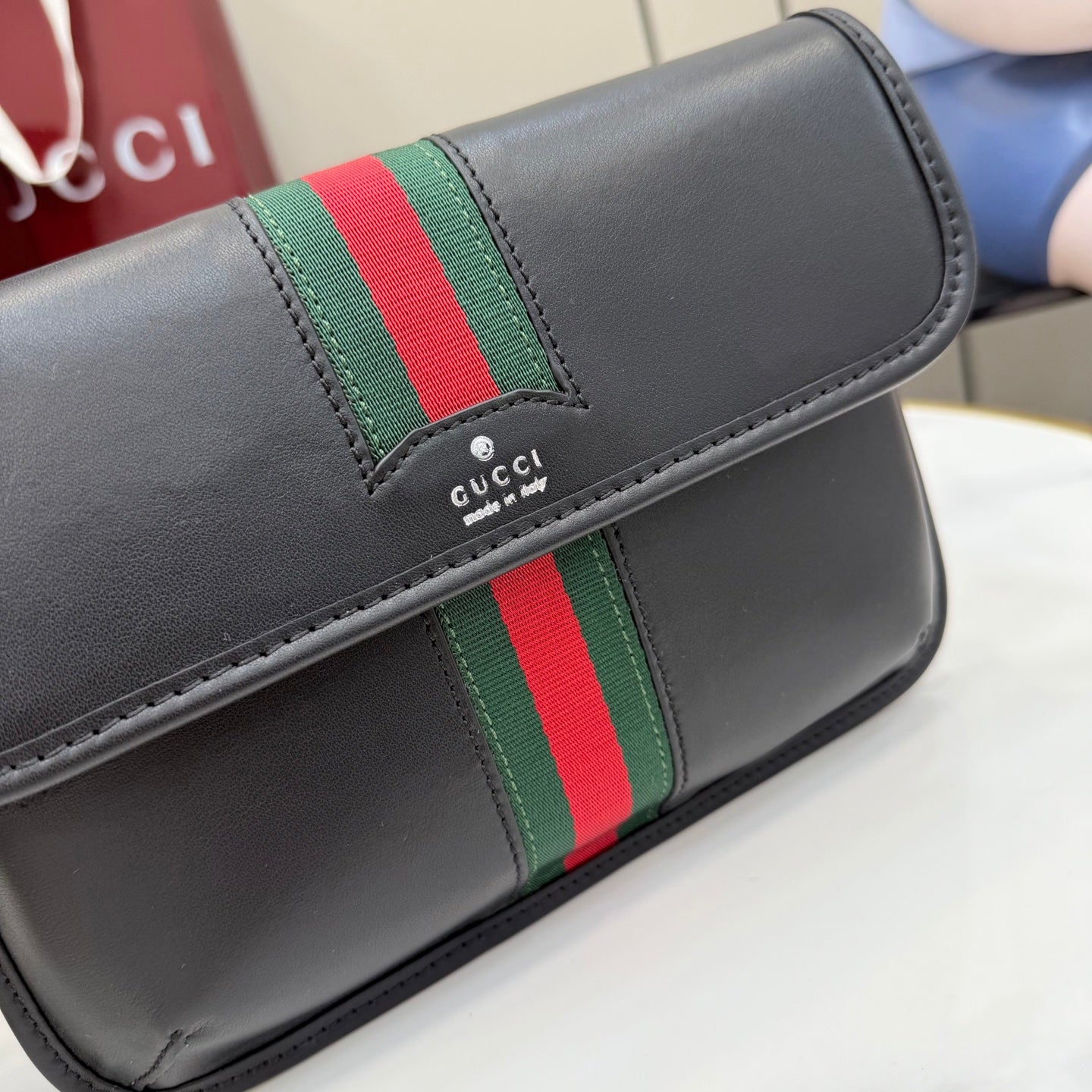 Gucci black bag close-up with green-red web stripe and stitched edge