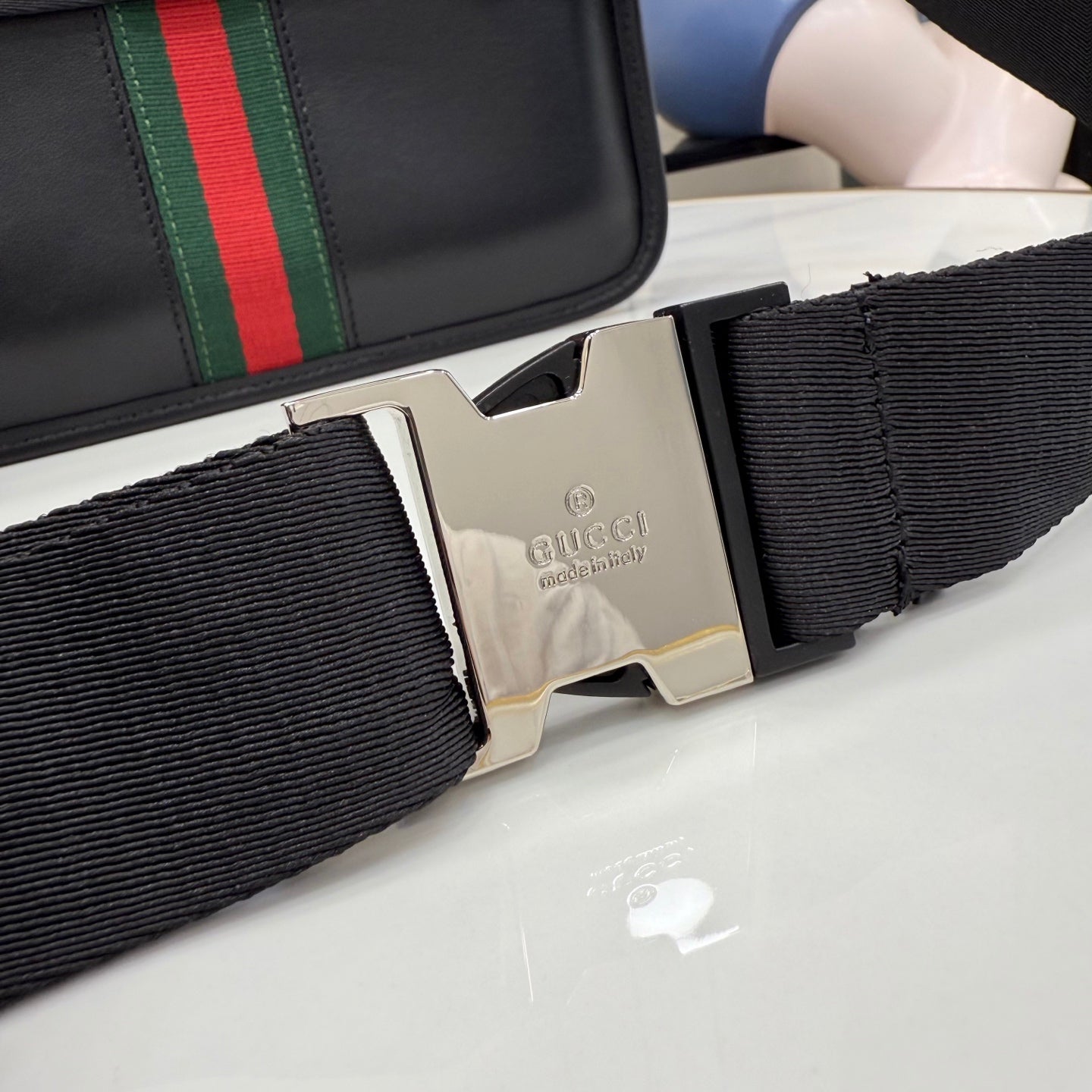 Gucci strap hardware with silver buckle and engraved logo on dark woven webbing
