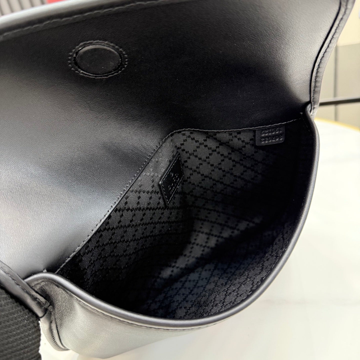 Gucci bag interior view with dark patterned lining and stitched inner seam