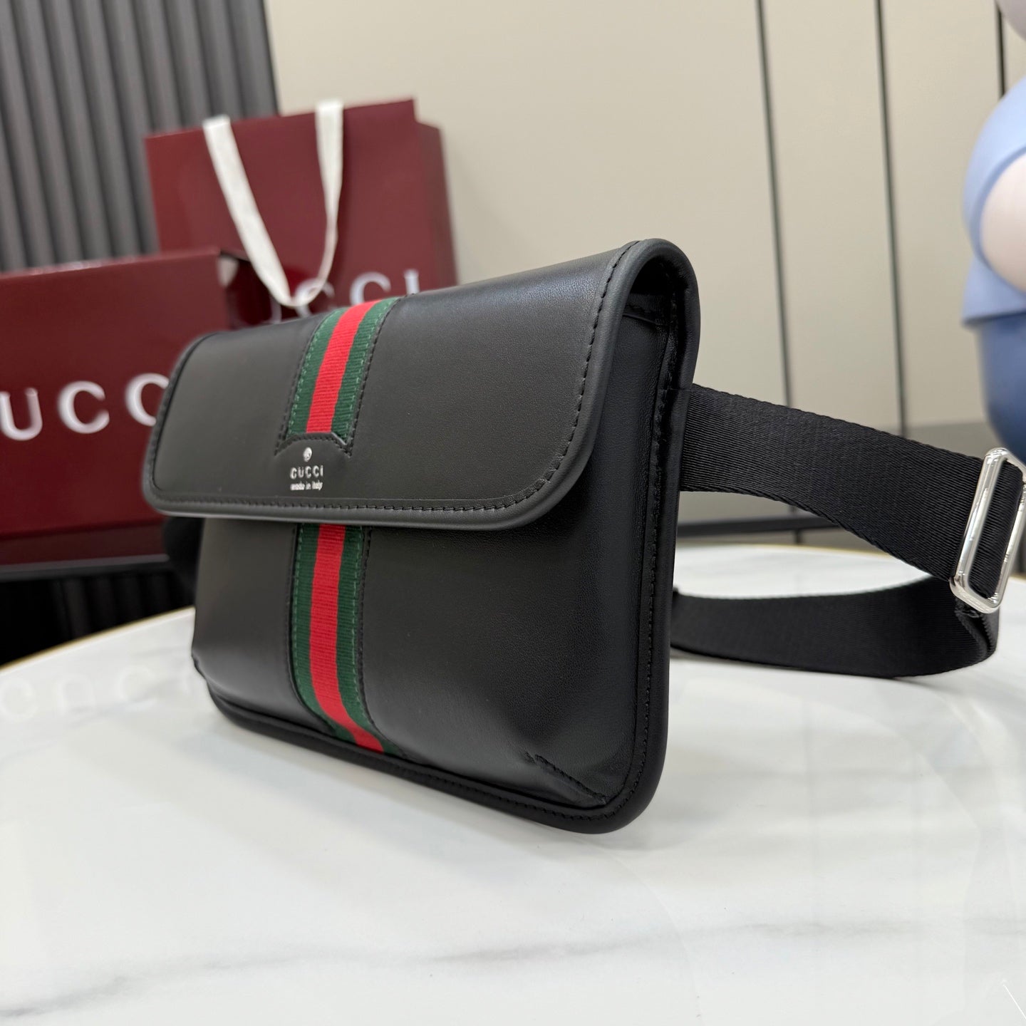 Gucci black crossbody bag side view with green-red web stripe and metal ring