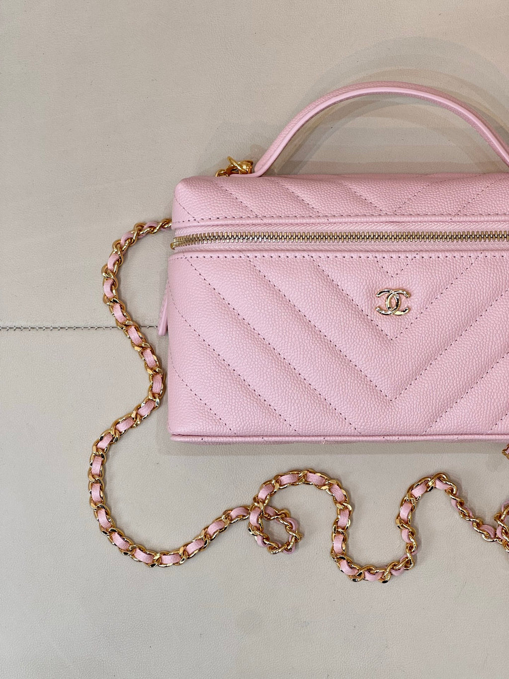 Pink quilted Chanel mini handbag with front zipper and gold chain shoulder strap
