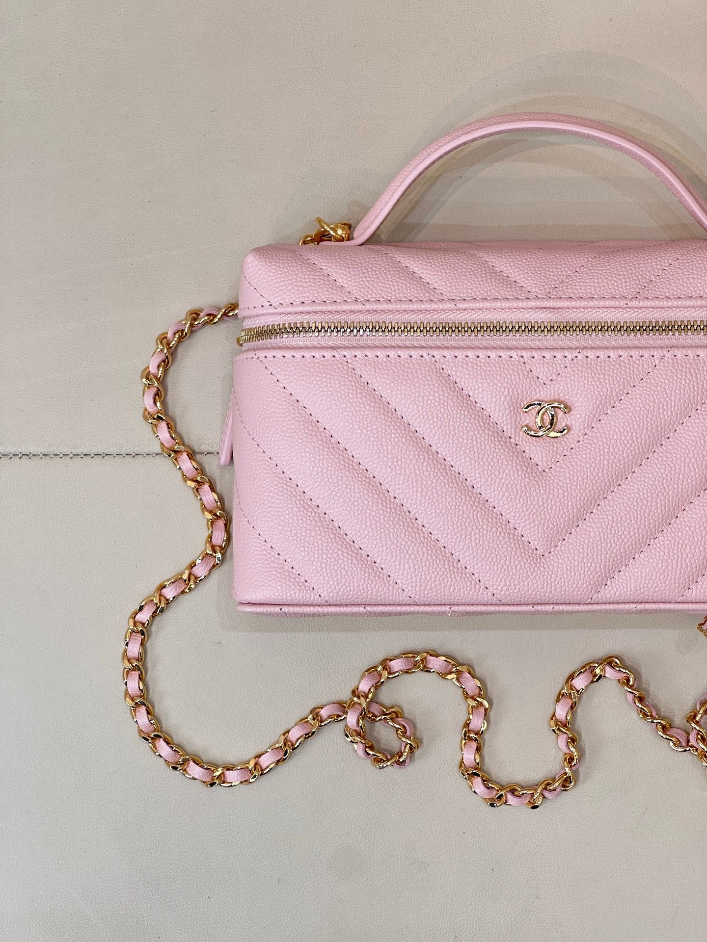 Pink quilted Chanel mini handbag with front zipper and gold chain shoulder strap