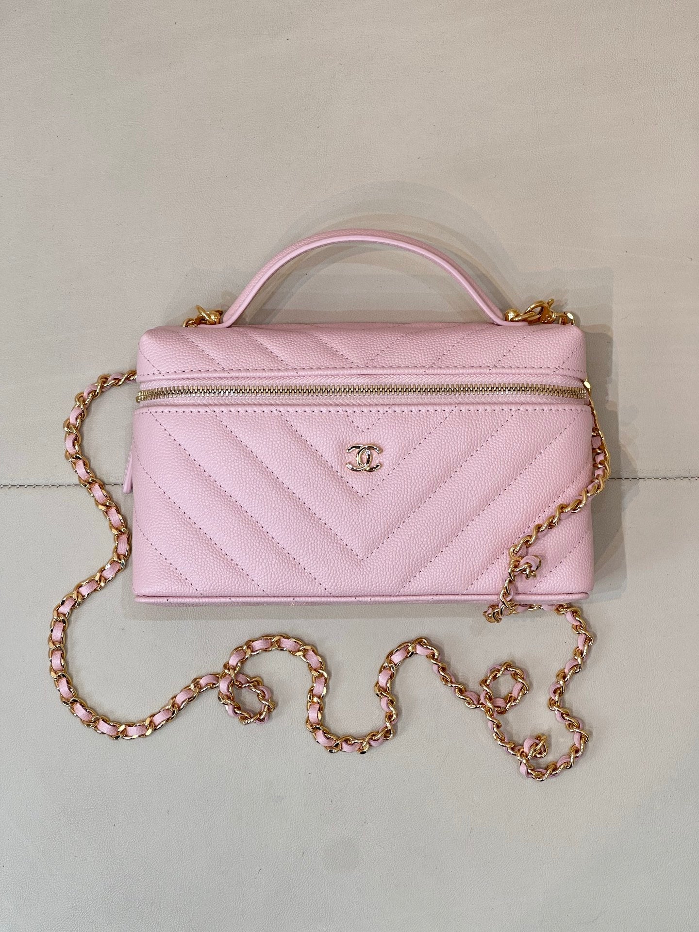 Pink quilted Chanel mini handbag with structured top handle and gold chain strap