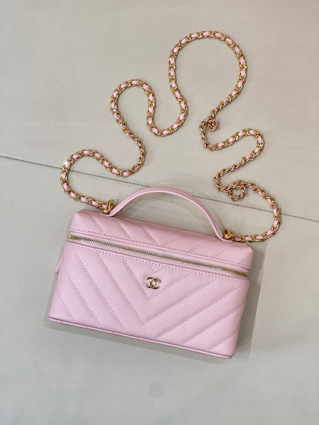 Pink quilted Chanel mini handbag with curved top handle and gold chain strap