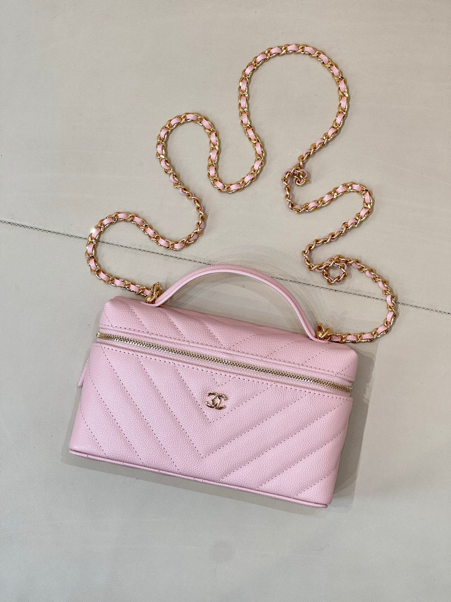 Pink quilted Chanel mini handbag with curved top handle and gold chain strap