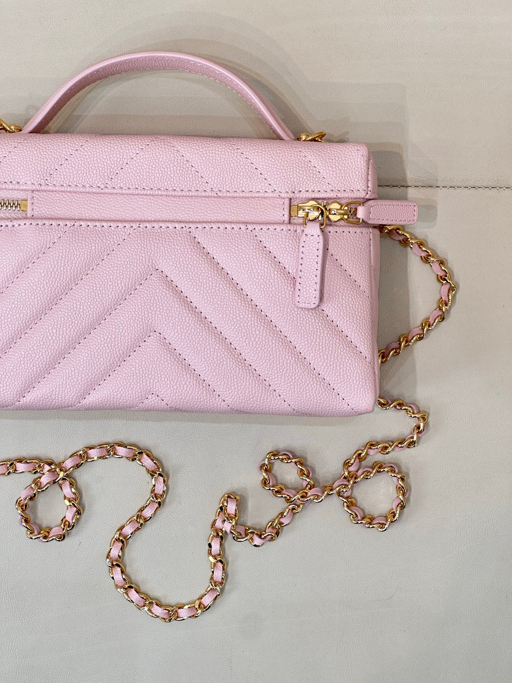 Close-up of pink quilted Chanel mini handbag with gold clasp and chain strap
