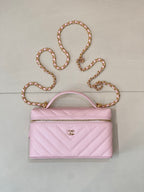 Pink quilted Chanel mini handbag with top handle and gold-tone chain strap