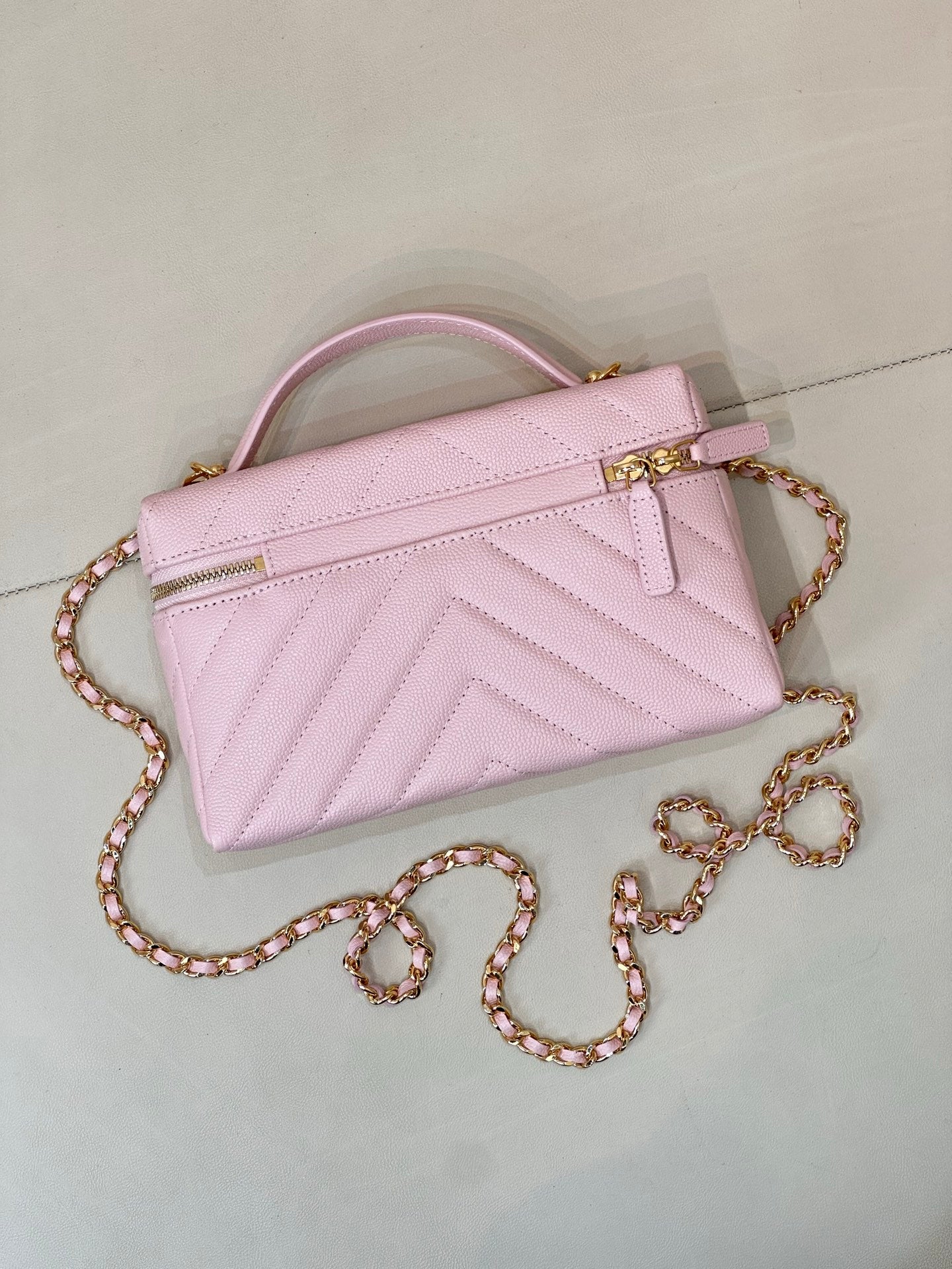 Pink quilted Chanel mini handbag with front clasp, top handle, and gold chain strap