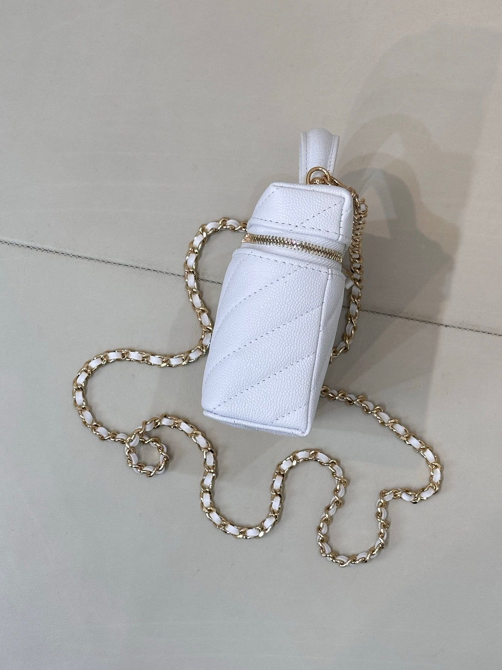 Light blue quilted mini pouch bag with gold chain and zip top