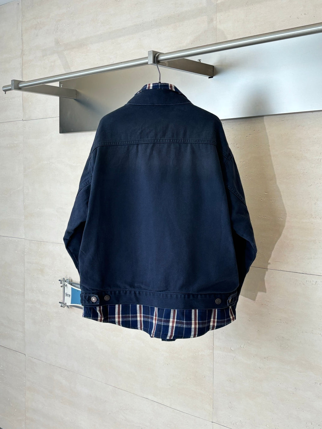Denim jacket back view with plaid hem at bottom, long sleeves, button details