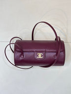 Burgundy leather mini shoulder bag with gold CC emblem and curved top handle