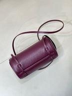 Burgundy leather cylindrical mini bag with structured top handle and crossbody strap