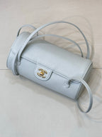 Light blue Chanel handbag with rolled top, gold logo front and long adjustable strap