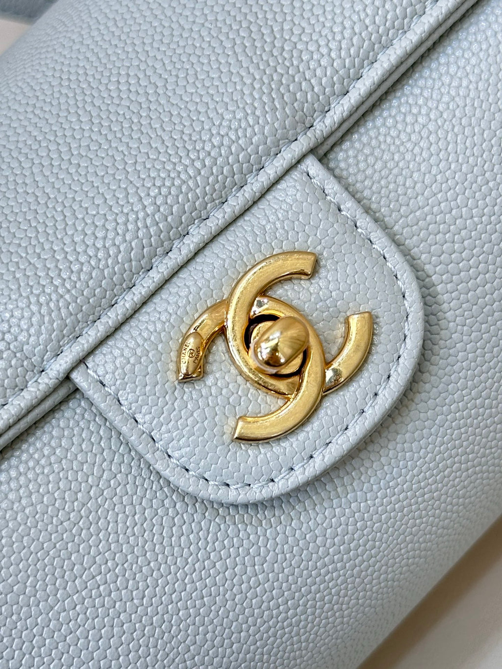 Light blue Chanel handbag corner detail with gold interlocking logo on flap