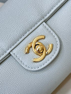 Light blue Chanel handbag corner detail with gold interlocking logo on flap