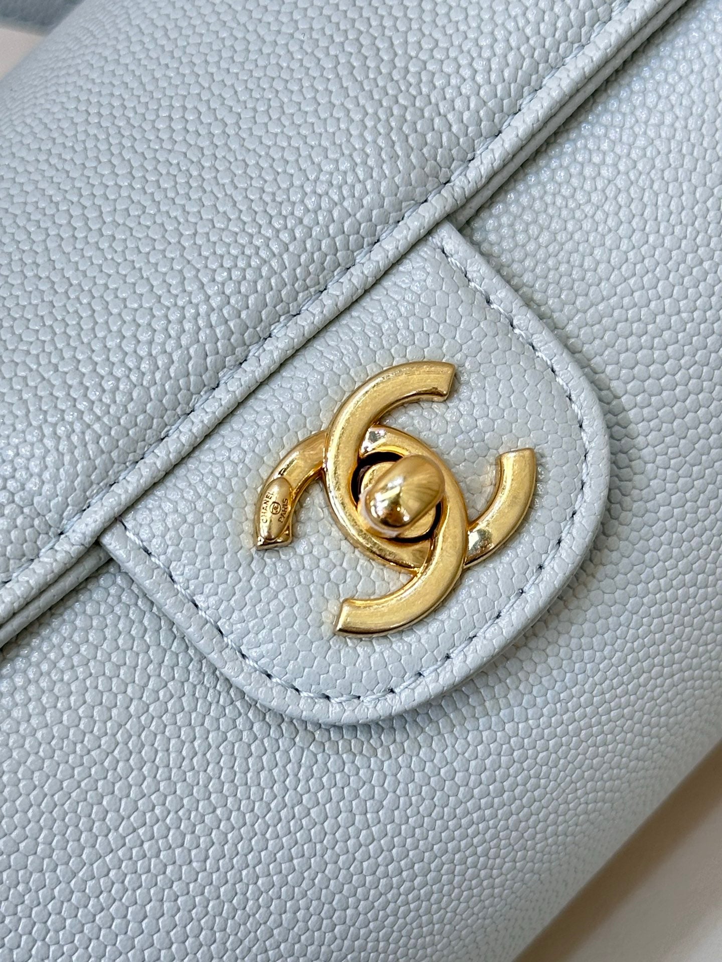 Light blue Chanel handbag corner detail with gold interlocking logo on flap