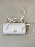 Chanel white leather small handbag with top handle, crossbody strap, and gold logo clasp.
