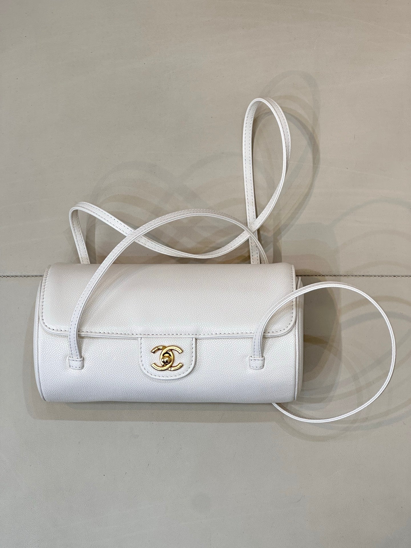 Chanel white leather small handbag with top handle, crossbody strap, and gold logo clasp.