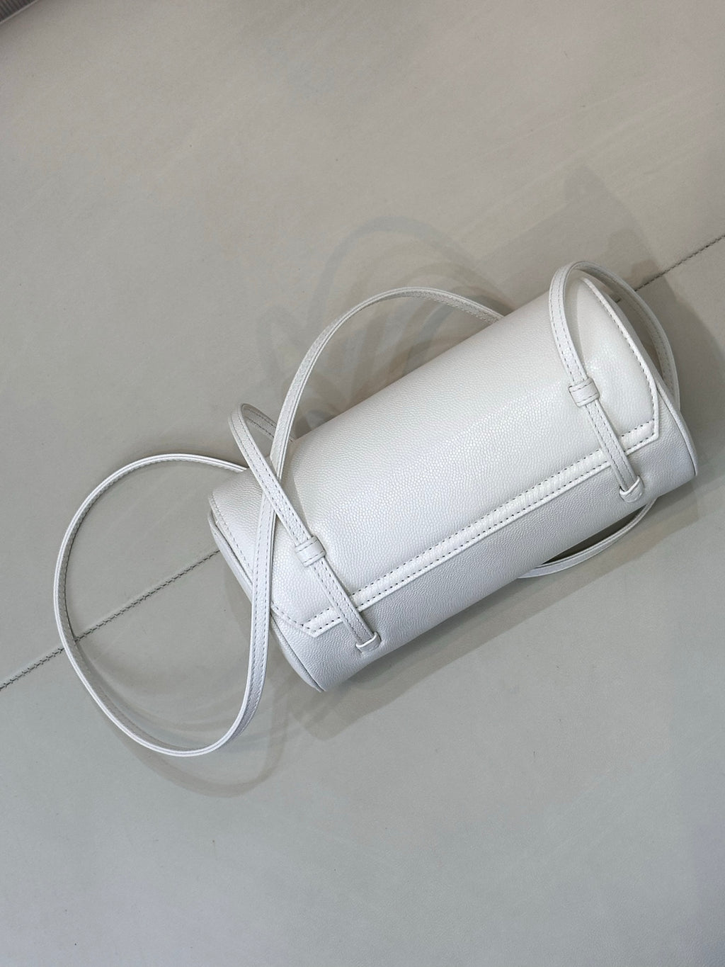 Chanel white leather cylindrical handbag with strap, stitched seams, and gold hardware.