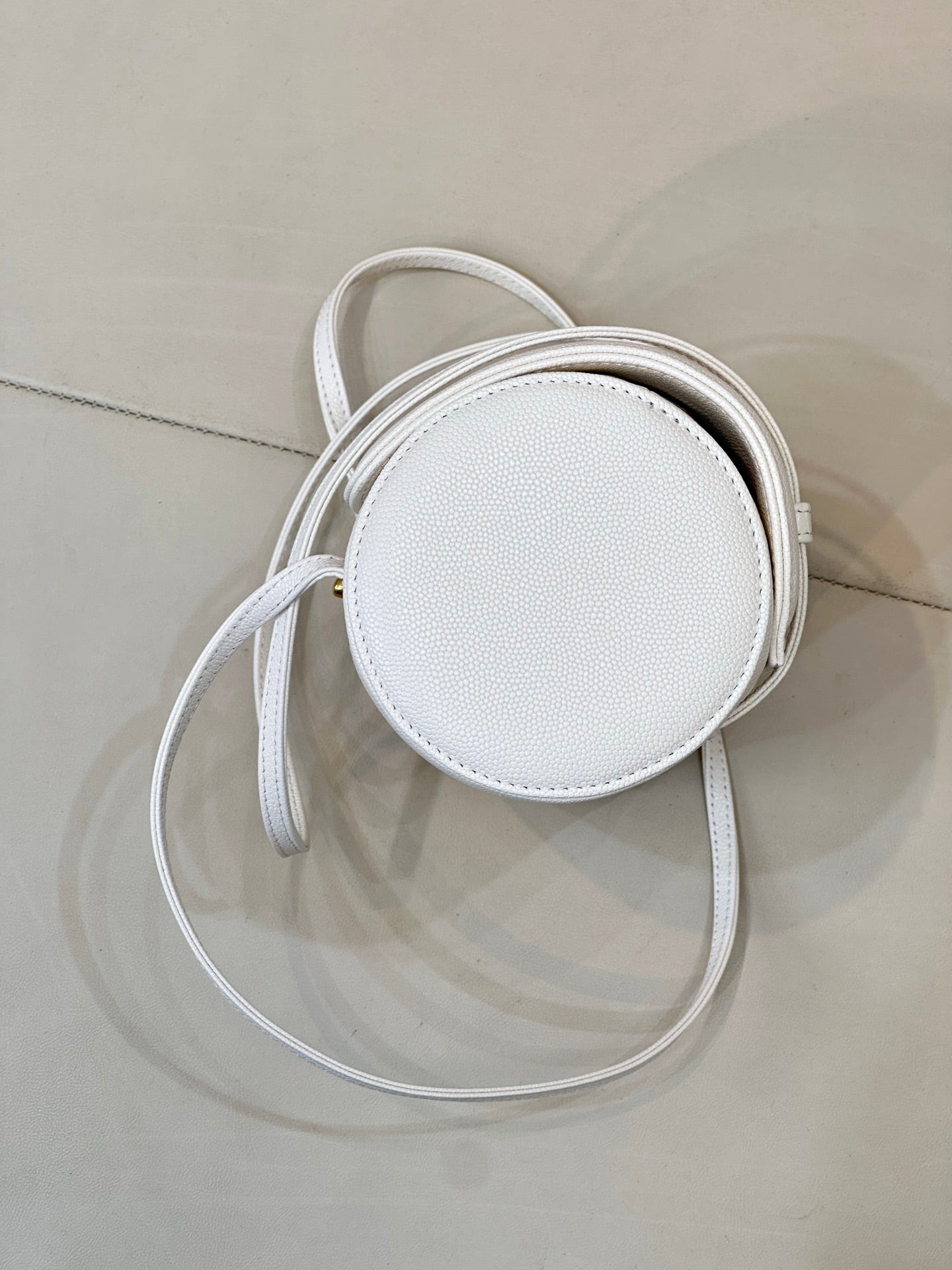 Chanel white leather round crossbody bag with thin strap and gold hardware loop.