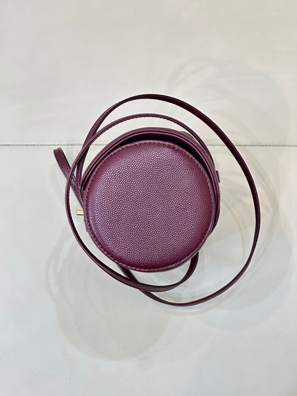 Burgundy leather mini bag round top view with thin crossbody strap and small handle