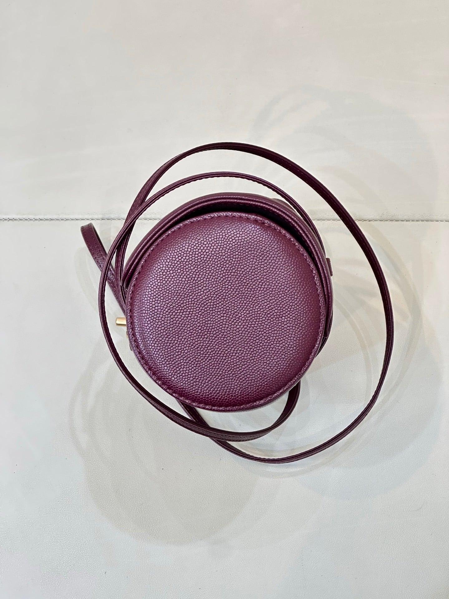 Burgundy leather mini bag round top view with thin crossbody strap and small handle