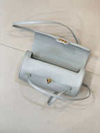 Light blue Chanel handbag top view with flap closure and gold clasp hardware