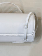 Chanel white leather handbag close-up of side strap attachment and stitched edges.