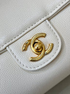 Chanel white leather bag close-up of gold CC turn-lock on front flap.