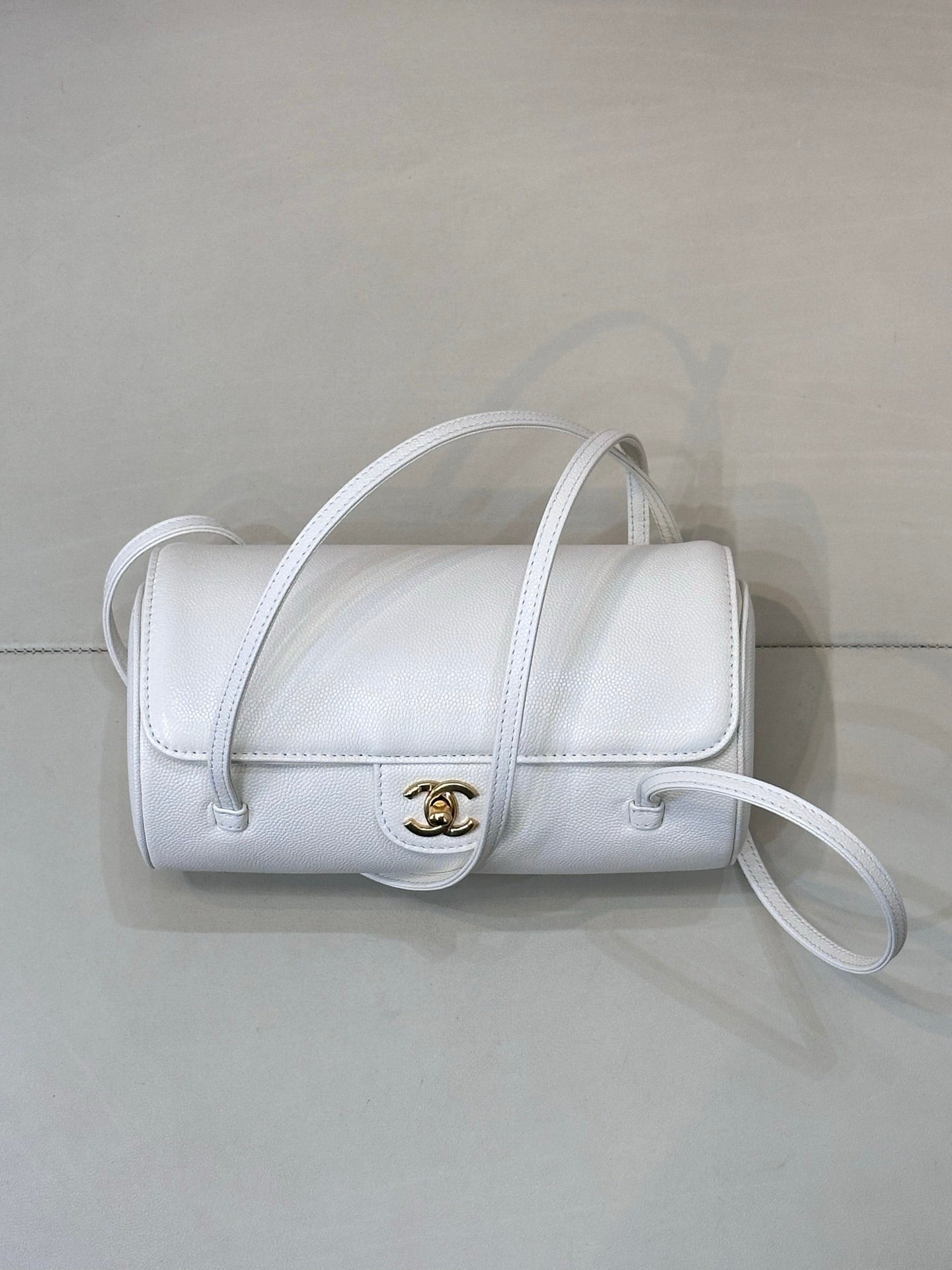 Chanel white leather mini handbag with flap, gold CC logo, and curved crossbody strap.