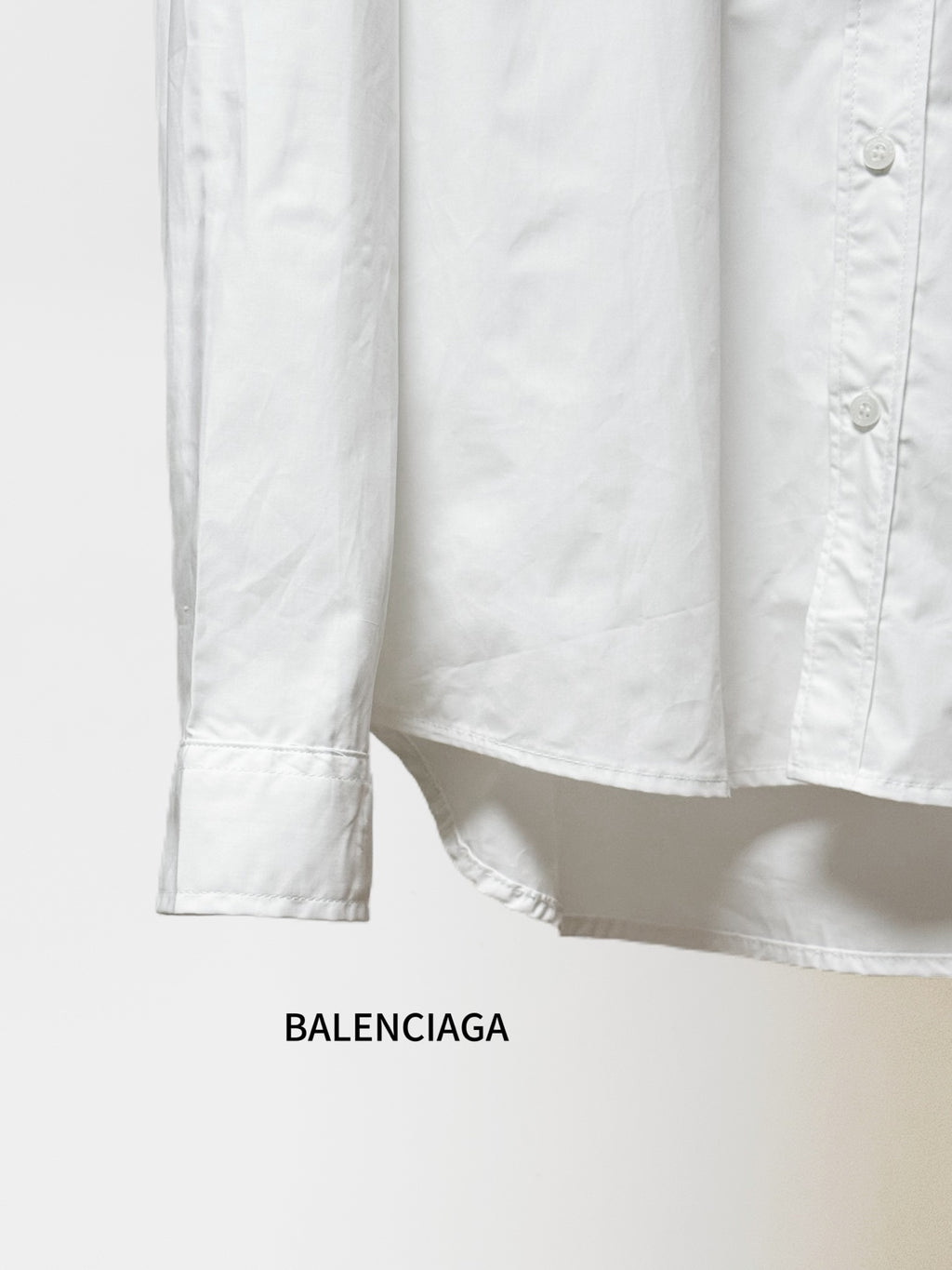 Balenciaga long-sleeve button-up shirt hem and cuffs, white fabric, straight hem.