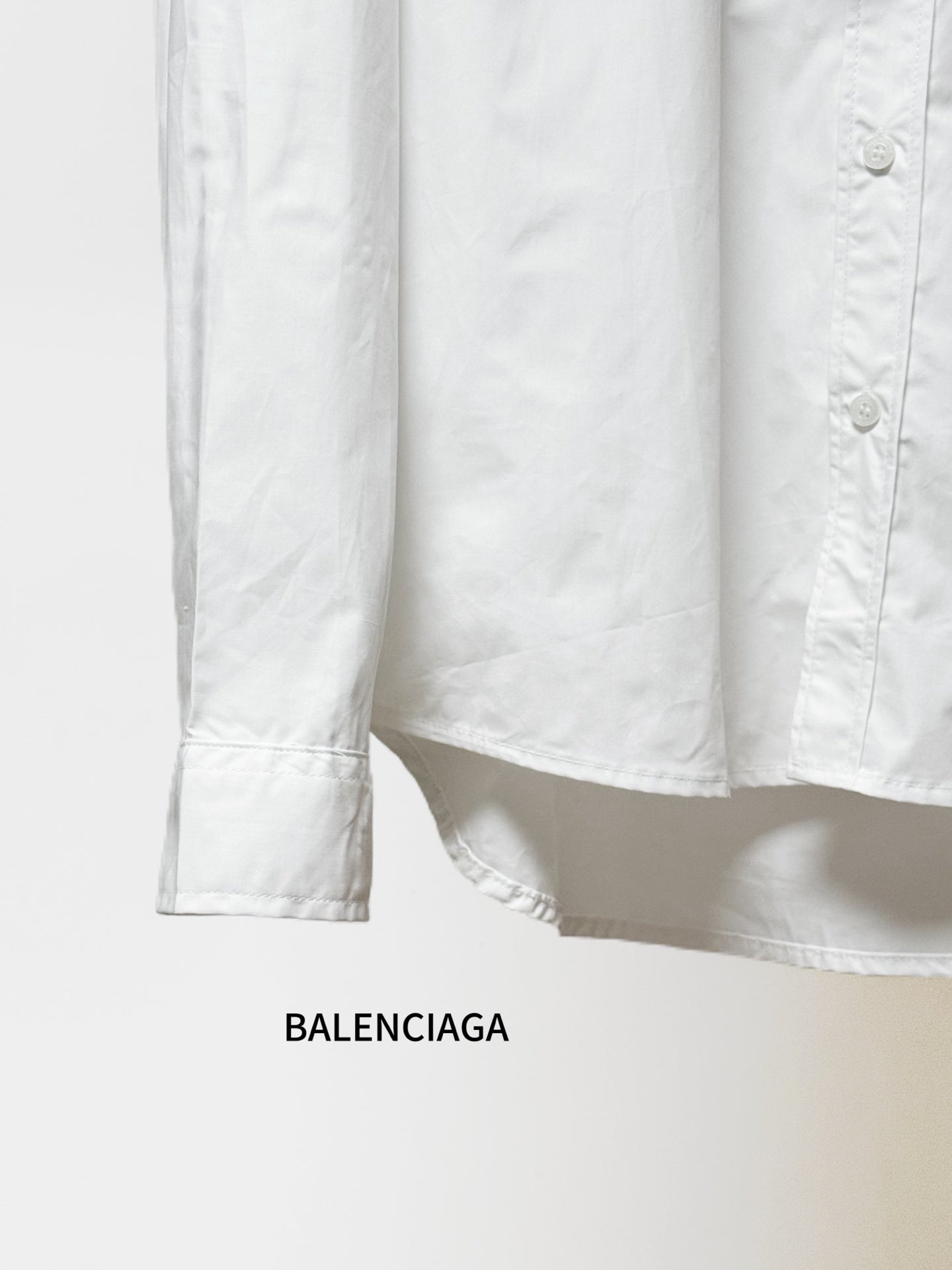Balenciaga long-sleeve button-up shirt hem and cuffs, white fabric, straight hem.