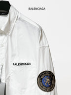 Balenciaga long-sleeve shirt close-up, white, with front logo and round sleeve patch.