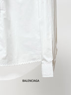 Balenciaga long-sleeve shirt lower back, white fabric with curved hem and sleeve cuff.