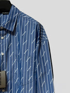 Blue button-up shirt shoulder with vertical pinstripe logo print and button cuff
