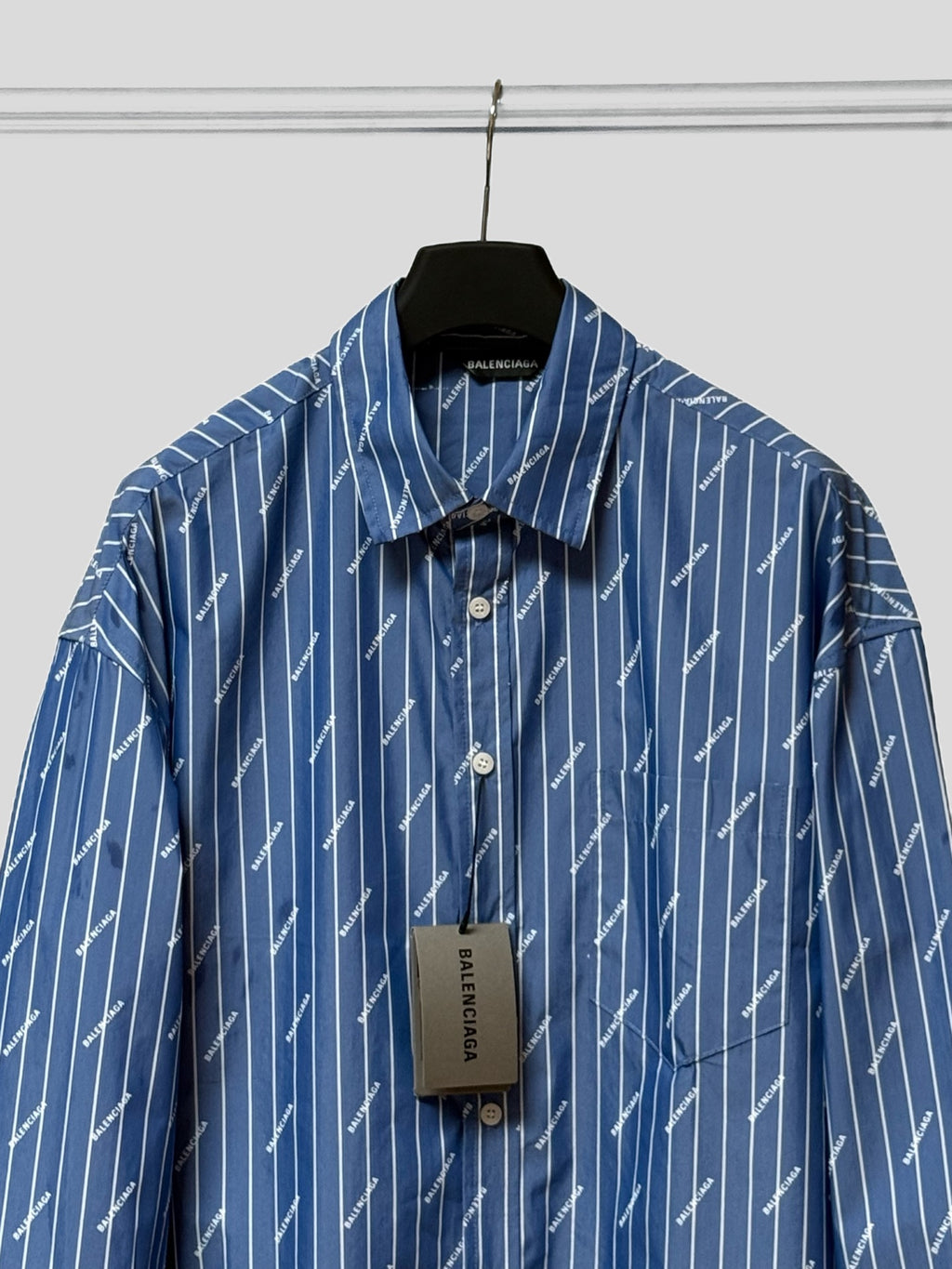 Blue button-up shirt with pointed collar, button placket, and hanging size tag