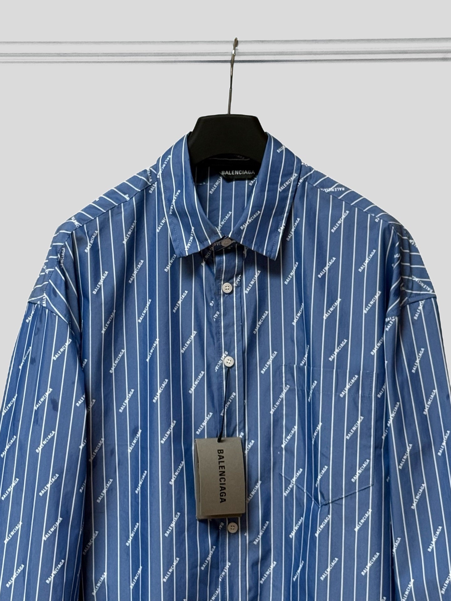 Blue button-up shirt with pointed collar, button placket, and hanging size tag