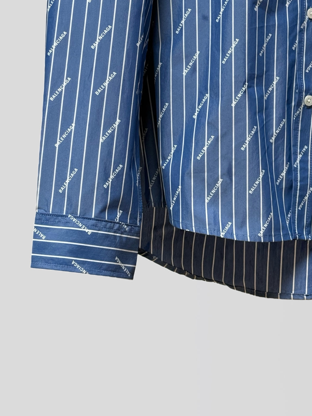 Blue button-up shirt hem with vertical pinstripe logo print and striped cuff