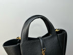 YSL tote bag close-up showing textured leather, handle opening, and gold charm on strap