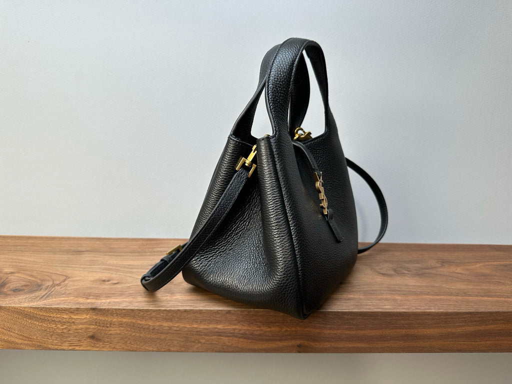 Black leather mini handbag angled view, gold hardware and shoulder strap