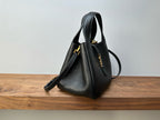Black leather mini handbag angled view, gold hardware and shoulder strap
