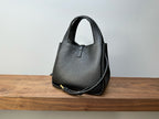 Black leather mini handbag with top handle and thin shoulder strap, structured shape