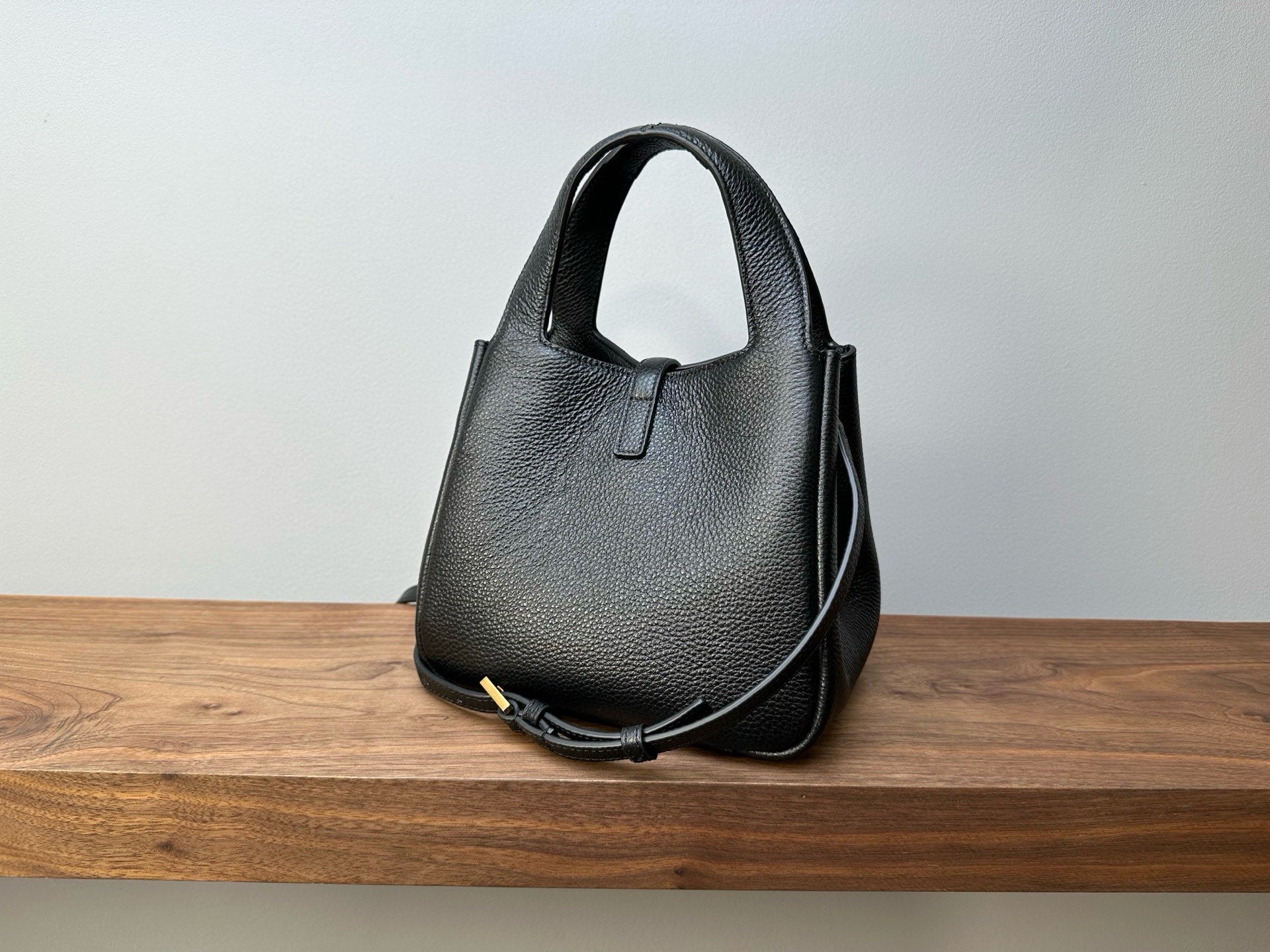 Black leather mini handbag with top handle and thin shoulder strap, structured shape