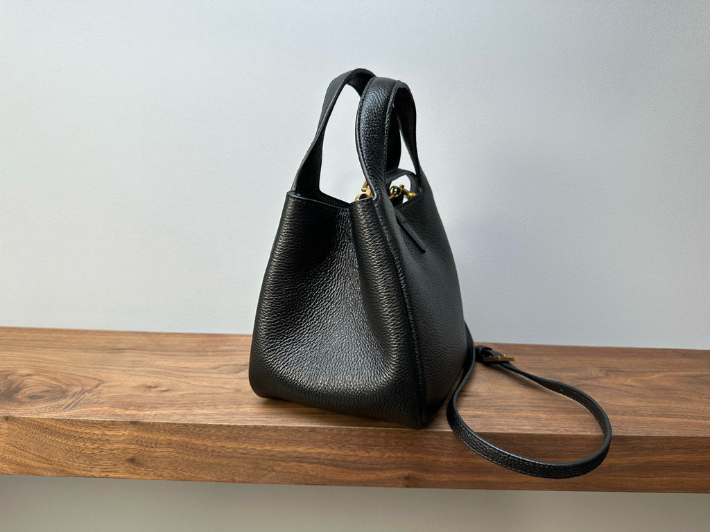 Black leather mini handbag side view with shoulder strap and gold-tone hardware
