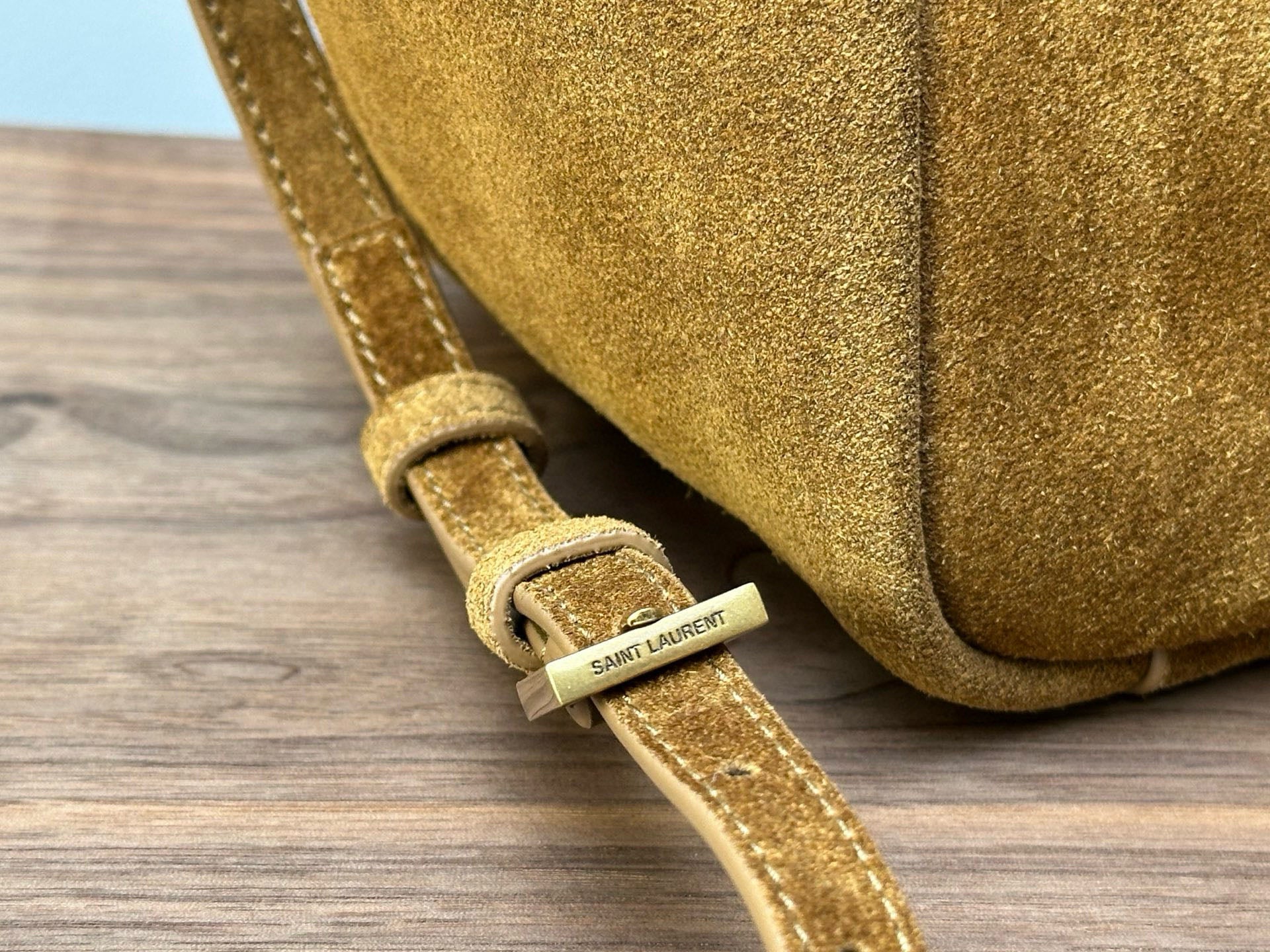 Gold suede strap with SAINT LAURENT label on tan mini tote bag strap