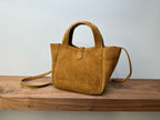 Tan suede tote bag with top handles and crossbody strap, structured shape