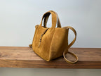 Tan suede tote bag with top handle and shoulder strap, front zip pocket detail