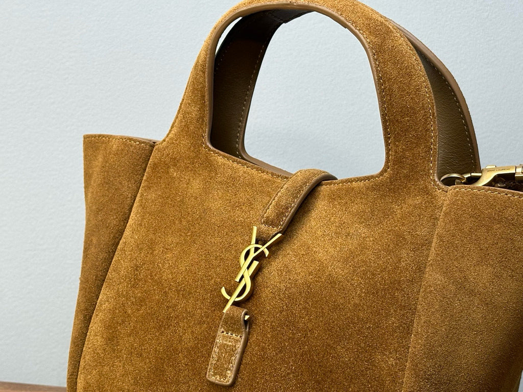 Tan suede tote bag close-up with YSL logo charm and small zip pull tag